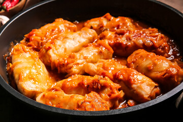 Frying pan with tasty stuffed cabbage rolls on wooden background