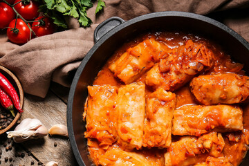 Frying pan with tasty stuffed cabbage rolls on wooden background