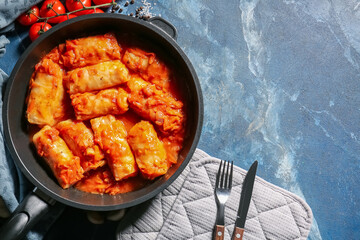Frying pan with tasty stuffed cabbage rolls on color background