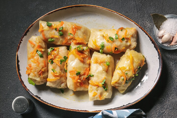 Plate with tasty stuffed cabbage rolls on dark background