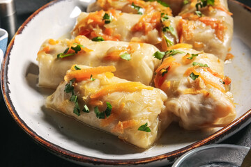 Plate with tasty stuffed cabbage rolls on dark background