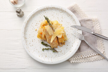 Plate with tasty stuffed cabbage rolls on light wooden background
