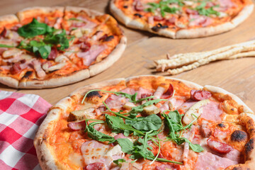 Three different pizzas on wooden table. Freshly baked traditional Italian Pizza over wooden background.