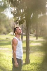 Man wearing white sleeveless t-shirt looking away in the park