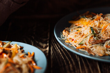 Two blue plates with salad on wooden background