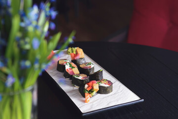 Maki Sushi set on a white plate over black background. Japanese cuisine concept, maki rolls.