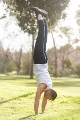 Man doing handstand on grass in the park.