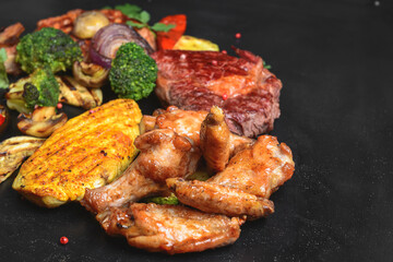 Hot spicy fried set. Grilled chicken, pork and beef over black background, with BBQ vegetables.