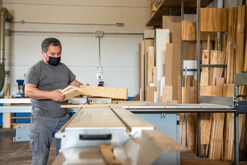 man cutting a wooden board into several pieces with a machine in a carpentry workshop to be processed, Ecological wood,