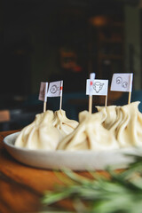 Khinkali cooked on a ceramic plate. Different kinds of Khinkali served on a wooden table, blurred background.