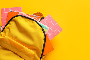 School backpack with stationery on color background