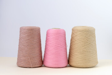 Pastel color bobbins of wool yarn for hand and machine knitting on a white background