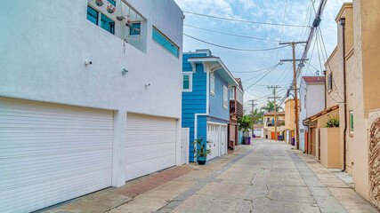 Naklejka premium Pano Neighborhood street in Long Beach CA with houses featuring attached garages
