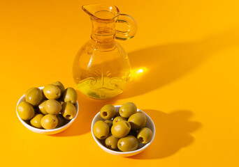 olive oil and olives on yellow background