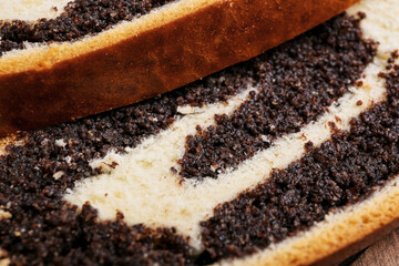 Tasty cut poppy seed bun on table, closeup