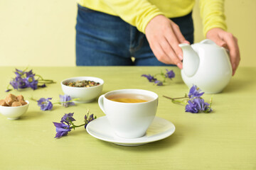 Cup of floral tea on color wooden table
