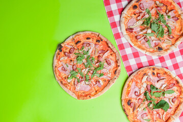 Delicious italian pizzas served on green table. Three pizza on rbright green screen background, copy space banner.