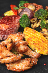 Hot spicy fried set. Grilled chicken, pork and beef over black background, with BBQ vegetables.