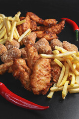 Hot spicy deep fried set. Deep fried chicken, cheese camembert and french fries over black background.