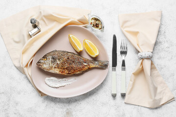 Plate with fried dorado on light background