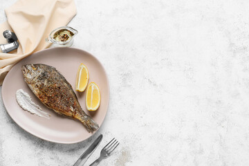 Plate with fried dorado on light background