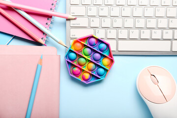 Pop it fidget toy, stationery and PC keyboard on color background