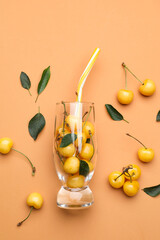 Glass with tasty sweet cherries on color background
