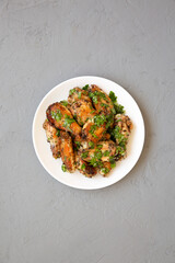 Homemade baked Garlic Parmesan Chicken Wings on a white plate on a gray background, top view. Flat lay, overhead, from above.