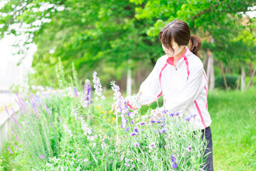 庭で花の世話をする若い女性