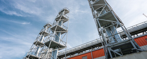 High steel plant piles in industrial estate against blue sky.