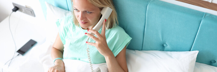 Woman lies on bed and dials number on phone