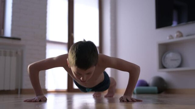 active healthy young kid making push-ups from floor during indoor training muscle sport leisure activity lifestyle