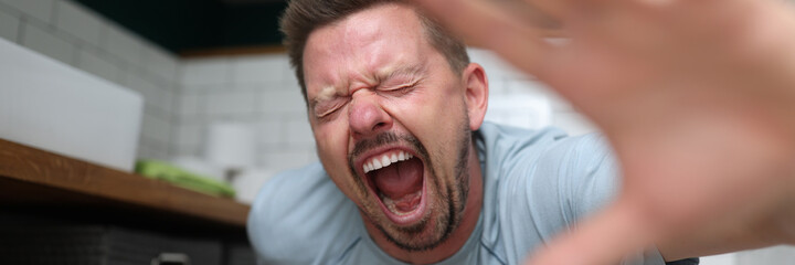 An emotional man sits in toilet and screams in pain