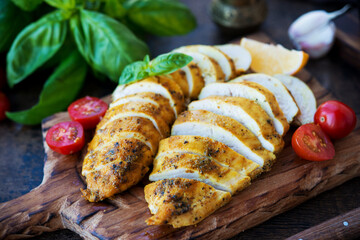 Baked chicken breasts on a wooden board with vegetables