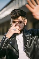Hipster young man with a beard portrait urban leather coat close up sunny day