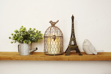 Wooden shelves decorated with Eiffel tower souvenir, candle light, flower bouquet and bird statue