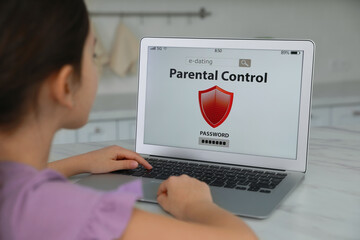 Little girl having access restriction by parental control on laptop in kitchen, closeup. Child...