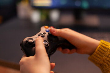 Close-up of professional cyber gamer holding joystick playing space shooter video game. Pro player use equipment during gaming tournament late at night in home studio using wireless controller
