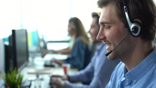 Male call center agent in headset helping client in customer support service