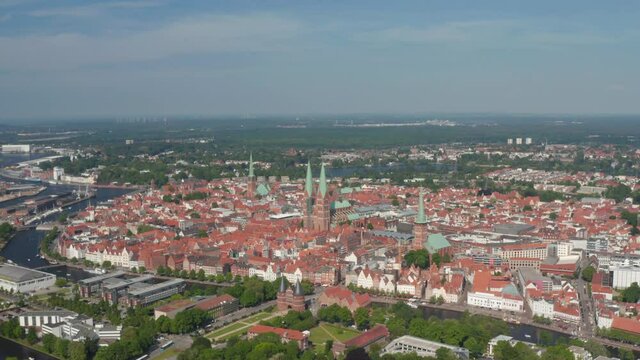Aerial panoramic view of medieval city centre lined with Trave river. Holsten Gate, St. Marys, St. Peters and St. Jacobs churches. Luebeck, Schleswig-Holstein, Germany