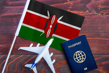 Flag of Kenya with passport and toy airplane on wooden background. Flight travel concept 