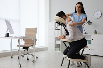 Man receiving massage in modern chair indoors