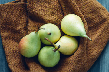 five small green and pink pears in a brown tea towel