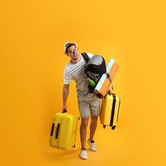 Male tourist with travel backpack and suitcases on yellow background - obrazy, fototapety, plakaty