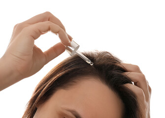 Mature woman applying oil onto hair on white background, closeup. Baldness problem - obrazy, fototapety, plakaty