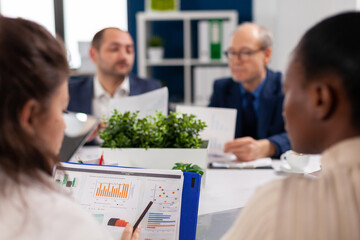 African american woman explaining charts during briefing in company boardroom. Multiethnic colleagues working planning success financial strategy discussing in office.