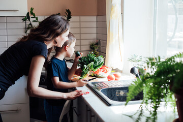 mother and son prepare a salad of vegetables in the kitchen