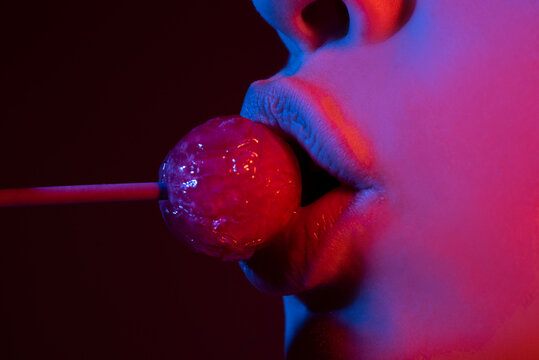 Sucking lips. Closeup female lips with pink lipgloss holding in mouth red lollipop candy. Lollipop on a face.