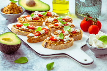 Bruschetta or open ciabatta sandwiches with avocado and tomato spread and feta cheese