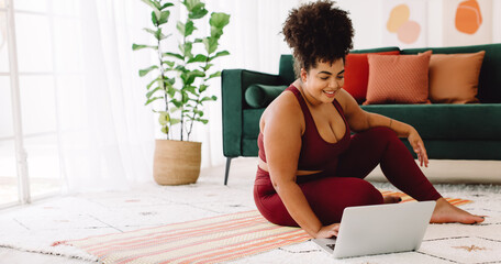 Fitness woman using laptop in exercise room at home